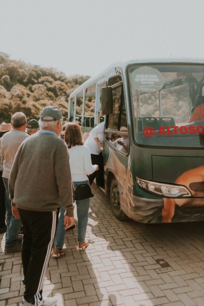 pexels photo 27757761 27757761 Group of people boarding a bus surrounded by nature, showcasing travel and transportation.