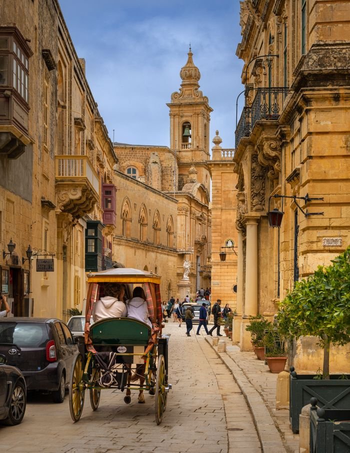 pexels photo 28539516 28539516 People enjoy a horse-drawn carriage ride on an ancient street in Mdina, Malta.