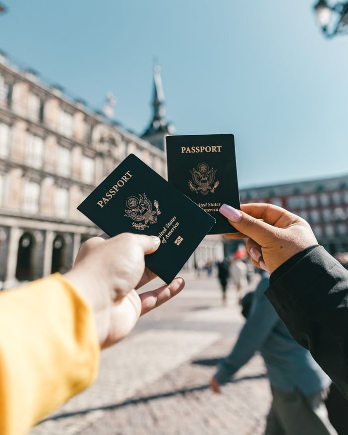 pexels photo 4353813 4353813 Crop unrecognizable travelers in casual clothes demonstrating passports of United States of America standing on square in historical city district